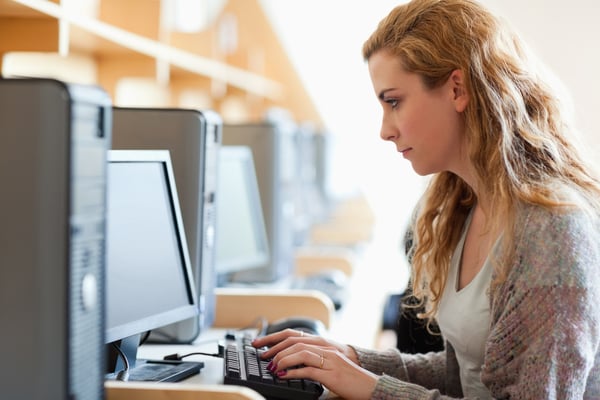 Cute student working with a computer in an IT room